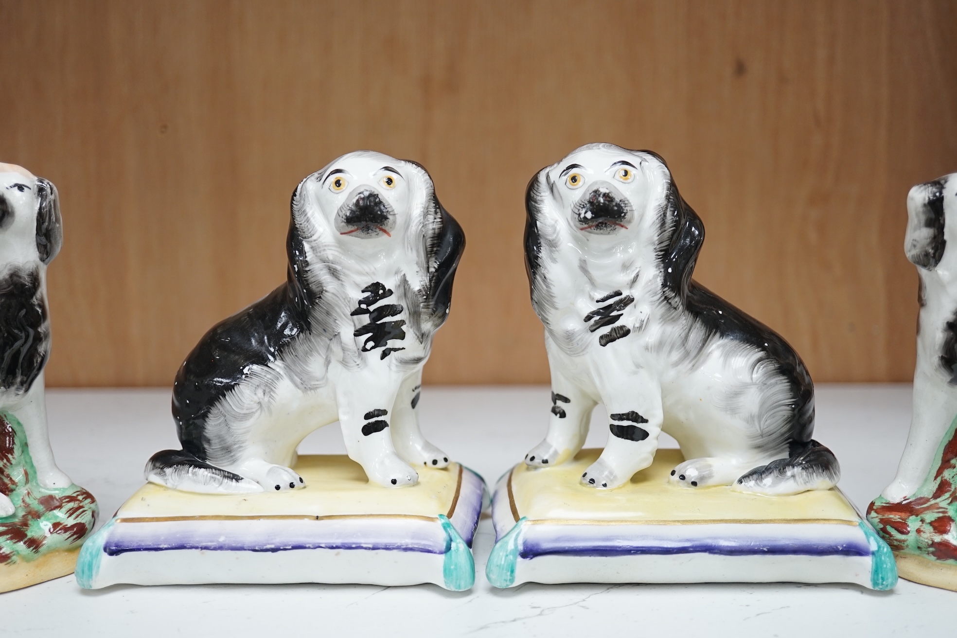 A pair of mid 19th century Staffordshire spaniels seated on cushions and a pair of similar groups of children riding spaniels (4), tallest 14cm. Condition - some minor flaking to paint, otherwise good